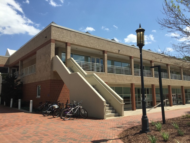 Exterior of Storrs Hall taken on a sunny day, UNC Charlotte, 2015. Staircase to the second floor and parked bicycles are prominent in the image.