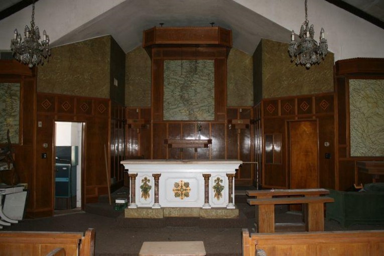 Interior features: the altar, inlaid wood paneling along the back wall, and chandeliers