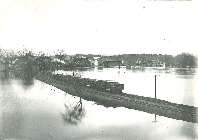 Undated image of a train full of lumber heading into the Contoocook Depot with high waters on both sides of the track.  