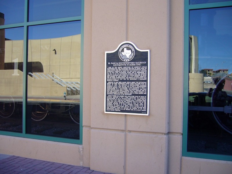 The historical marker is located outside on a column between two windows.