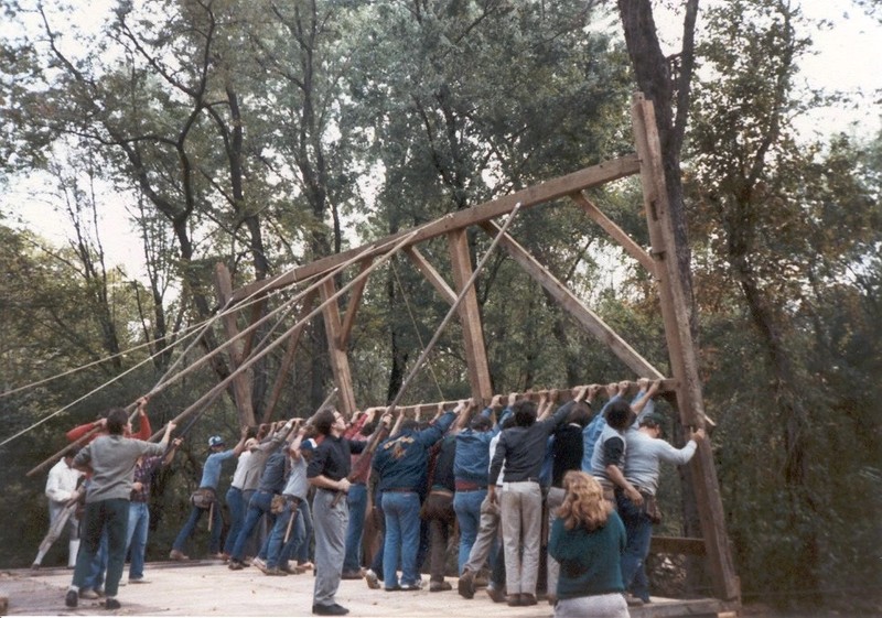 Image of a group of people lifting the framing for one side of the barn