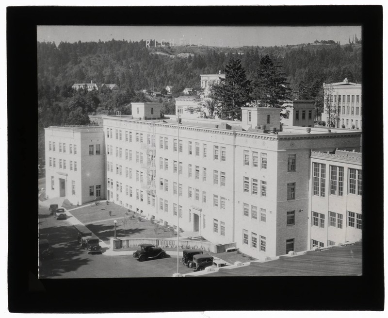  Black and white photograph of the exterior of University of Oregon Medical School Outpatient Clinic with the Richfield sign in the hills above campus.