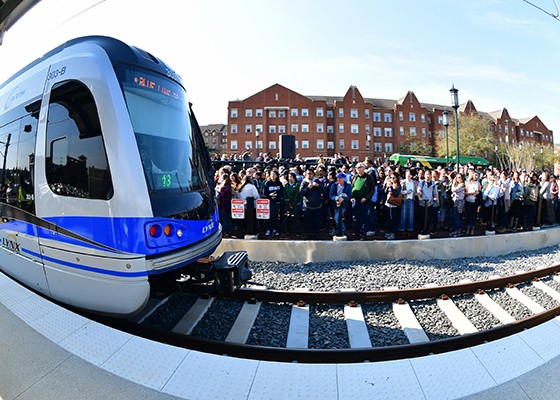 Crowds of students, faculty, and staff gather at UNC Charlotte Main Station to celebrate the opening day of the LYNX Blue Line Extension, March 16, 2018. Wallis Hall can be seen in the background.