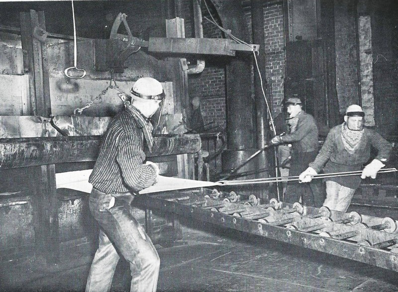 Workers pull a sheet of metal out of an annealing furnace, 1966