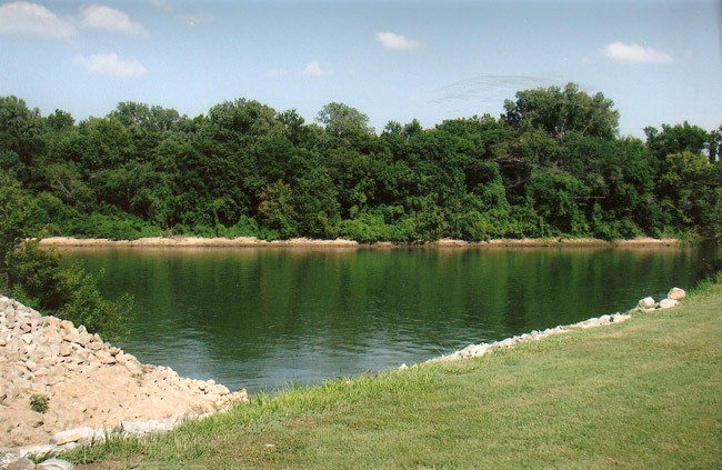 A colored picture of a river with banks and trees.