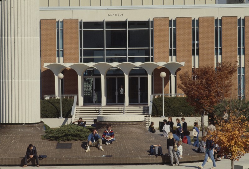 The Kennedy Building with several students out front. Belk tower to the left. Undated, color image.