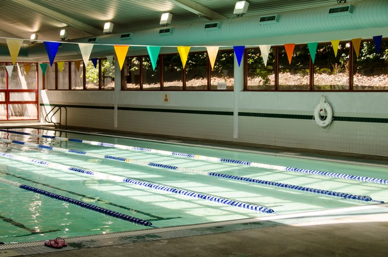 Color photograph showing an indoor pool with lane dividers with colorful triangular pennants hanging overhead.