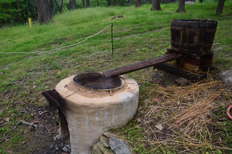 Lye is carried from the wooden ash barrel via a wooden trough and into the potash kettle.