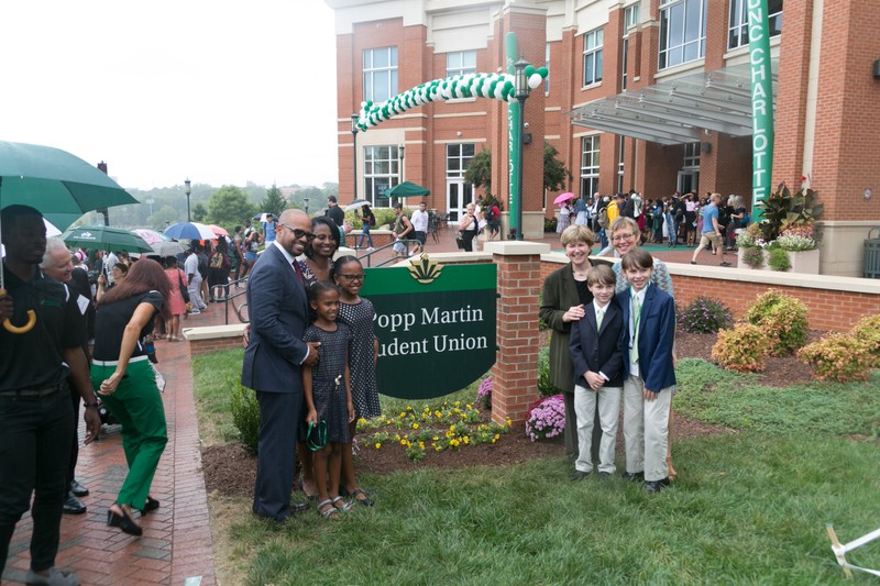 Karen Popp & Demond Martin posing for a picture around the Popp Martin Student Union sign with their families at the dedication ceremony.