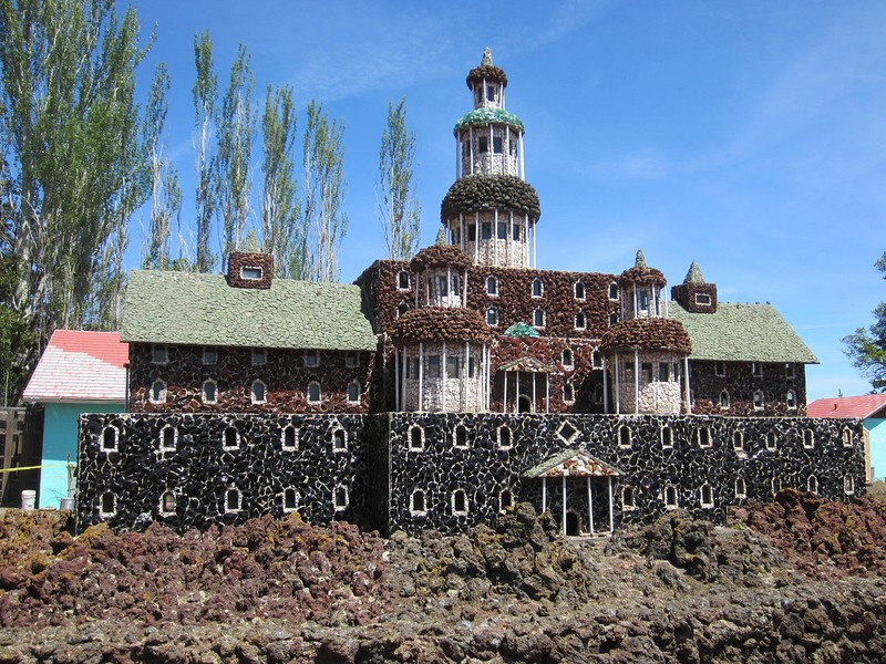 Petersen Rock Garden is a unique historical site in Oregon, featuring sculptures, bridges, and replica buildings made with rocks, shells, glass, obsidian, and petrified wood.