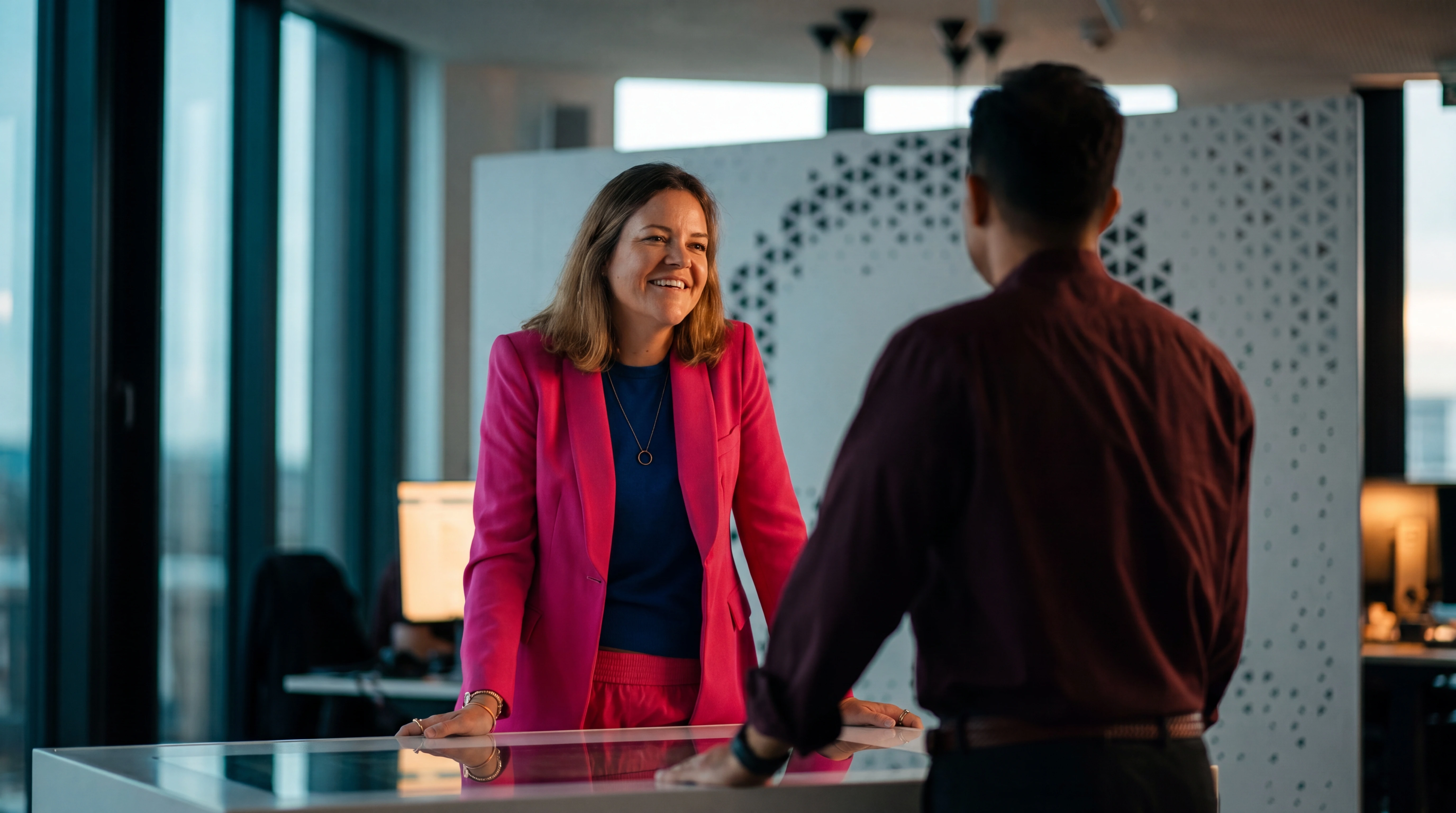 HRS Hybridfilm: KI-generierte Gesprächsszene mit einer Mitarbeiterin im pinken Anzug im HRS-Büro.