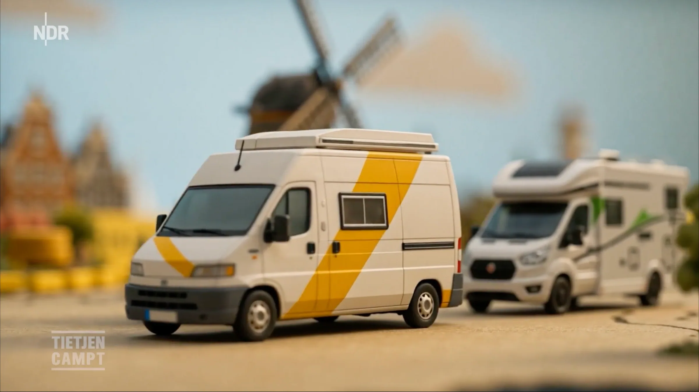 Still der Intro-Animation: Zwei Wohnmobile vor einer Windmühle in einer Miniaturlandschaft.
