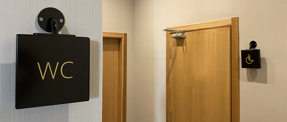 Señalización baños con placa de aluminio pintado y rotulado con vinilo dorado. Soporte especial de aluminio.