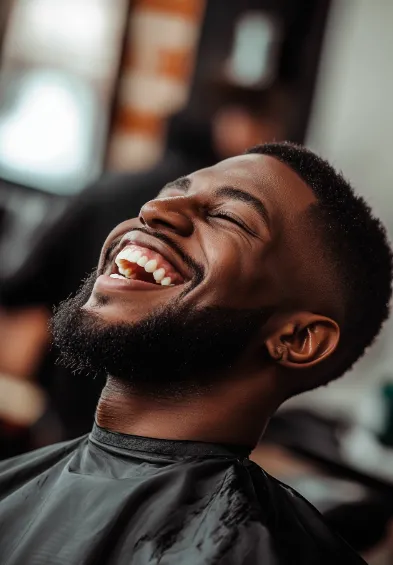 Smiling man in barbershop setting – symbol of trust, relaxation, and community comfort in men’s grooming culture