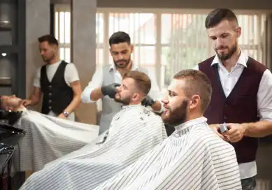Barbers providing a detailed beard trim and haircut, offering a professional grooming service in a well-equipped barbershop