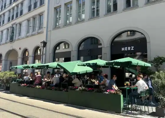 Außenterrasse des Herz von Frankfurt mit grünen Sonnenschirmen und Gästen in der Altstadt.