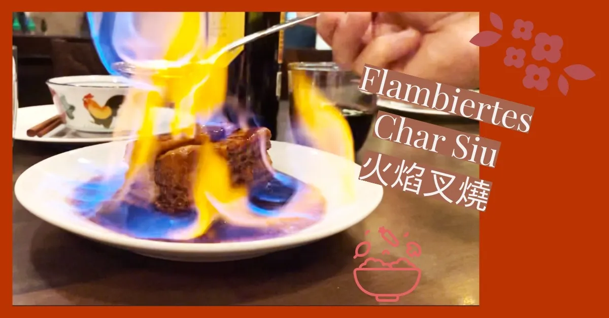 Flambiertes Char Siu mit Rosenschnaps – brennender Schweinebauch auf weißem Teller, serviert im chinesischen Restaurant mit traditionellem Geschirr.