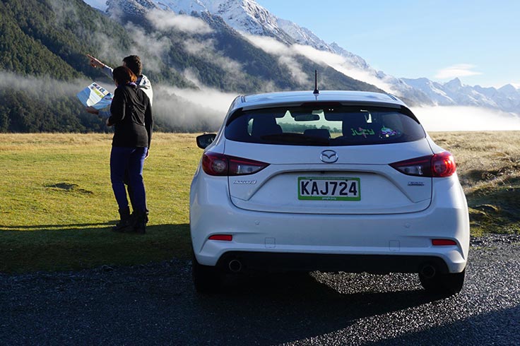 couple looks at map next to compact hatch