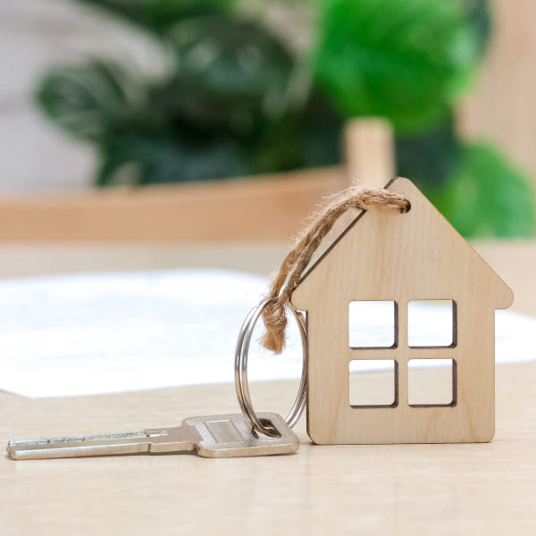 Porte-clés en bois représentant une clé et un stylo, symbolisant l'achat d'une maison.