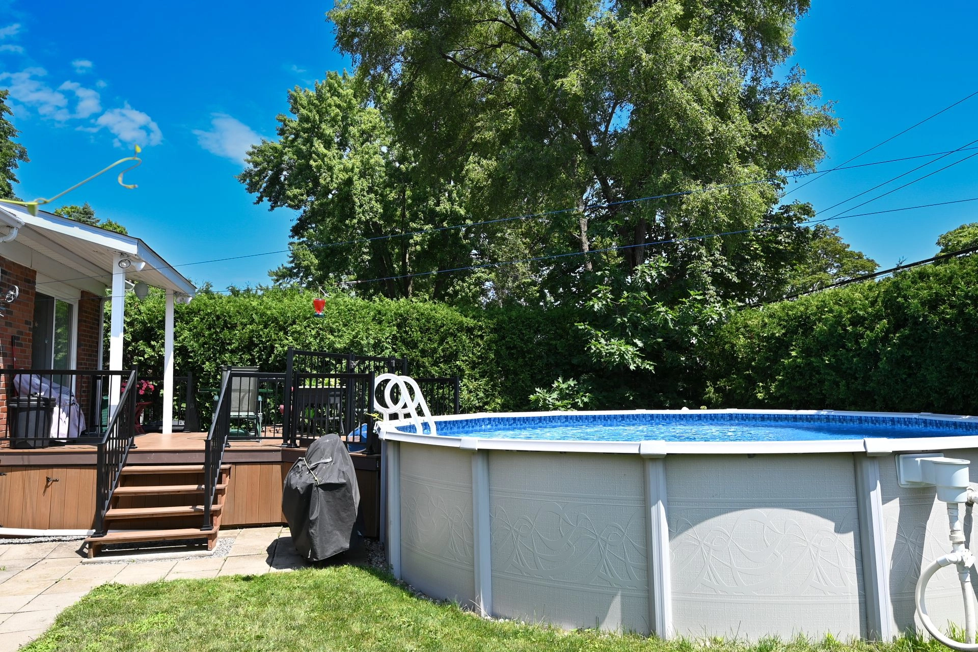 Elevated deck with railings and above-ground pool in a well-maintained garden.