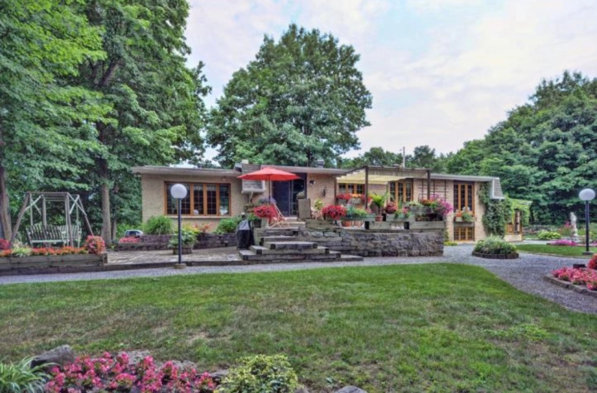 maison entourée de verdure avec terrasse et parterres de fleurs