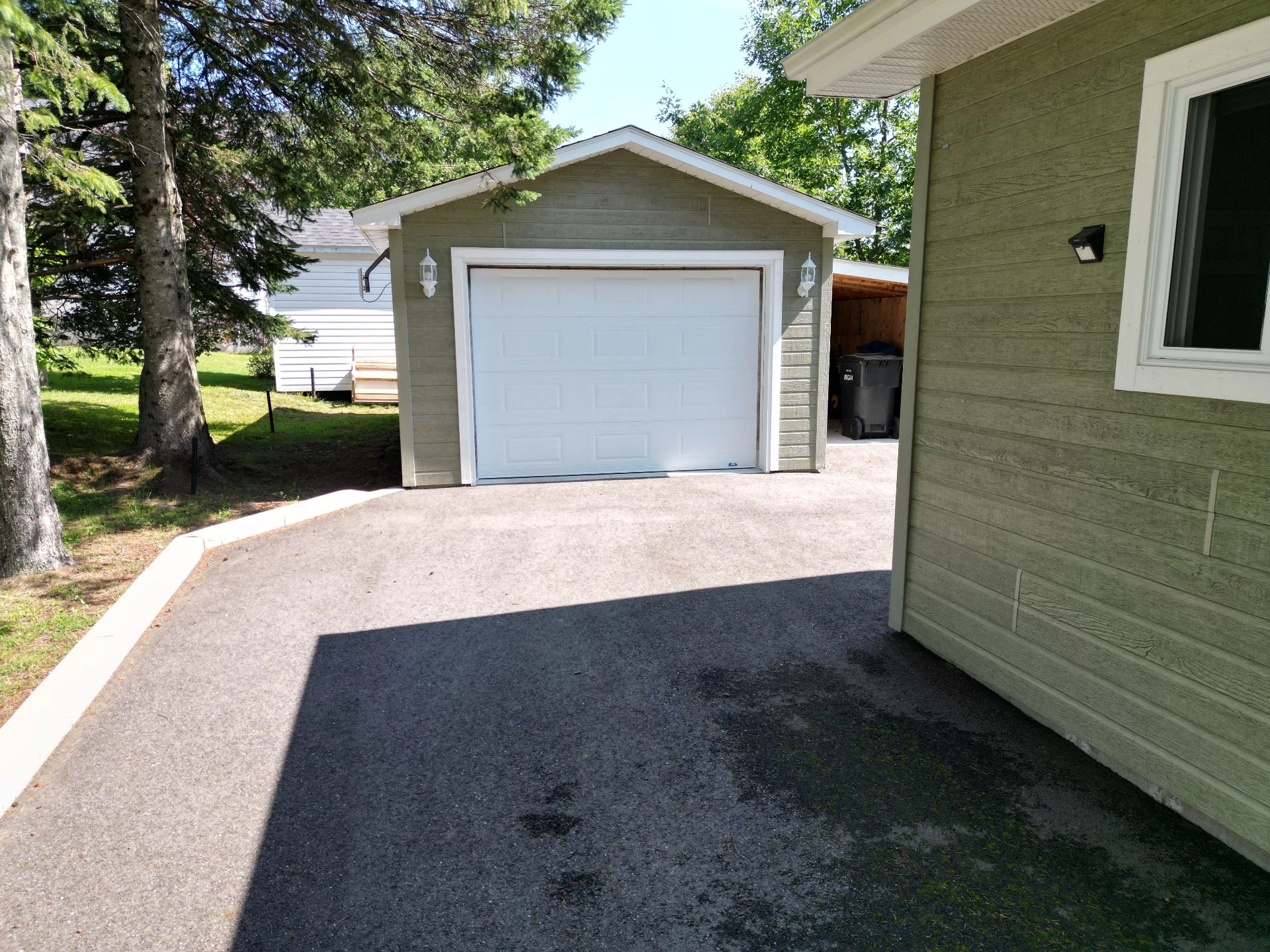 Entr&eacute;e de garage spacieuse avec all&eacute;e pav&eacute;e et arbres matures