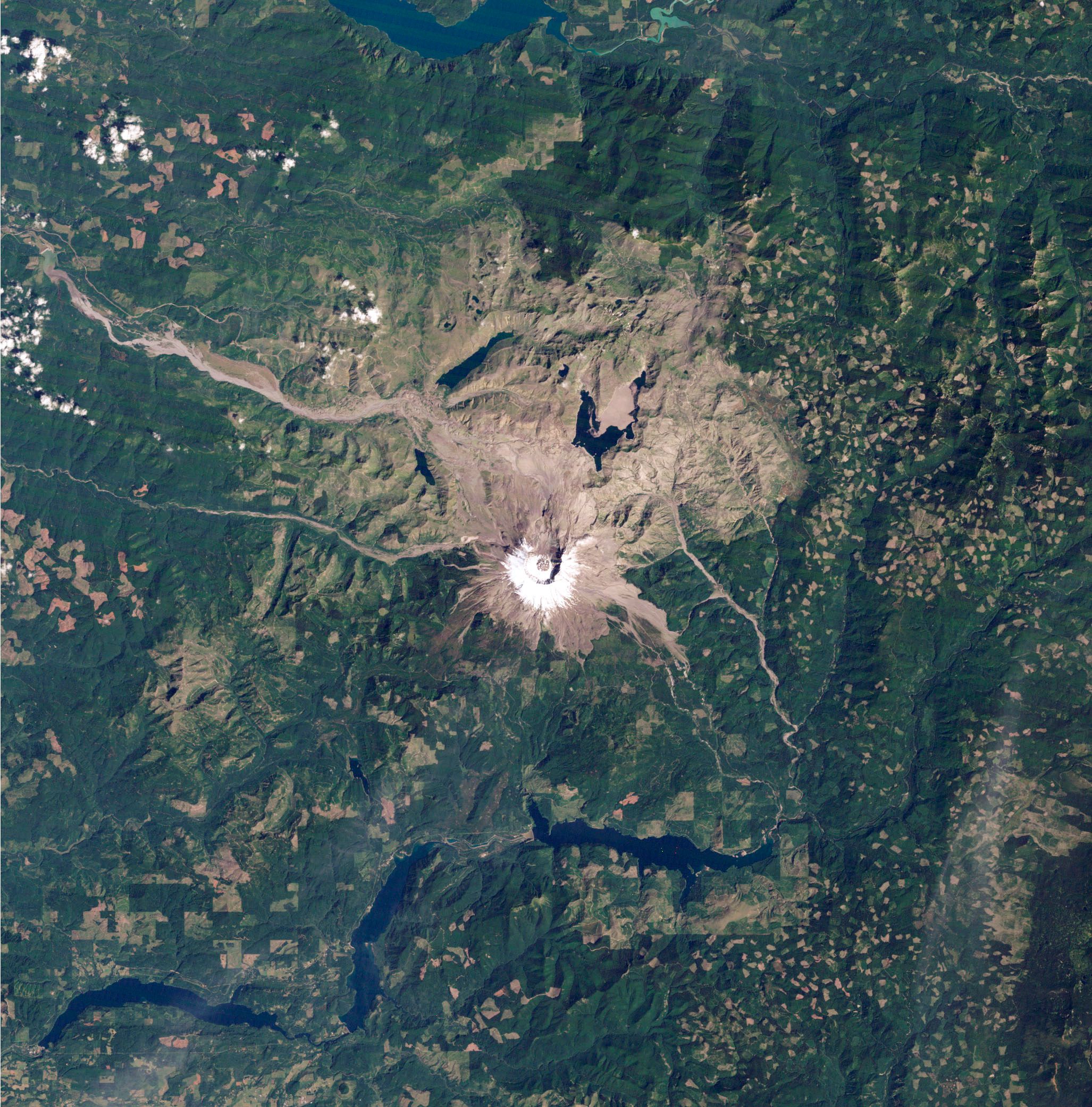 Eine Satelliten-Aufnahme zeigt den schneebedeckten Krater des Mount St. Helens, sowie seine grau-braune Vulkanlandschaft und eine grüne Umgebung.