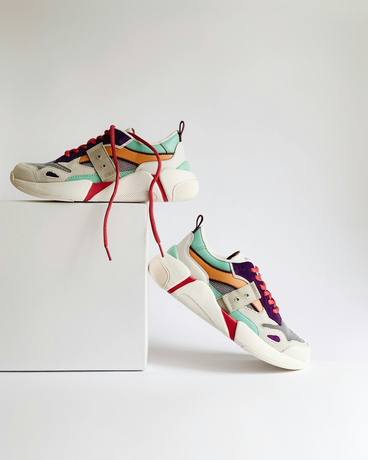 Colorful pair of classic clog-style shoes displayed on a bright outdoor surface, playful and casual