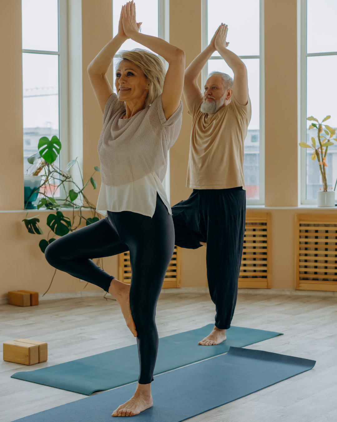 Woman and man doing tree pose with hands overhead and palms touching