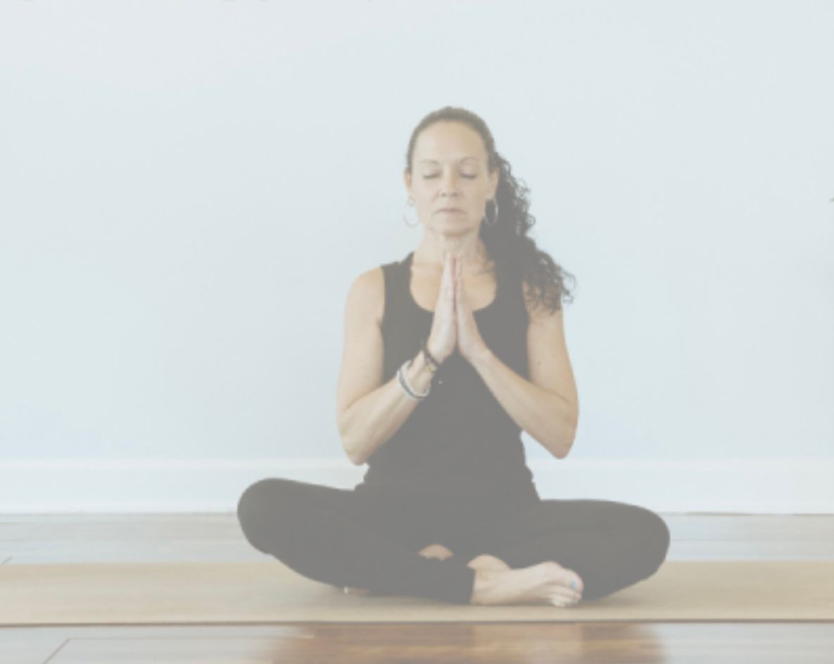 Yoga instructor in a dynamic seated pose with one arm and leg lifted, practicing on a mat in a calm indoor space