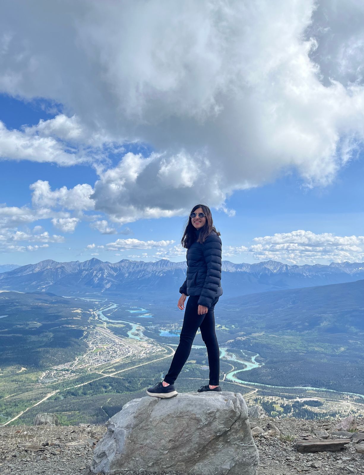 A woman standing on top of a mountain with the valley in the background