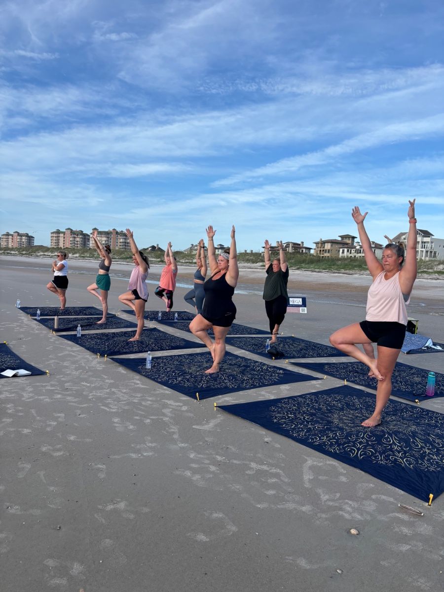 Women doing yoga on beach mats