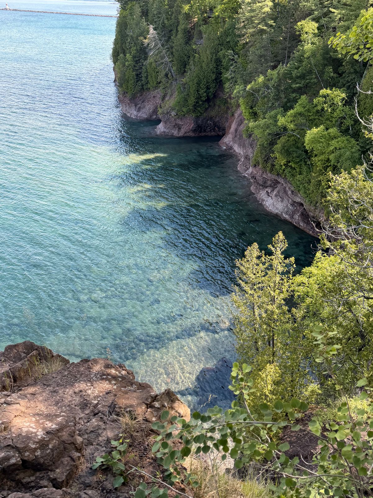 A rocky shoreline overlooking a lake and wooded landscape