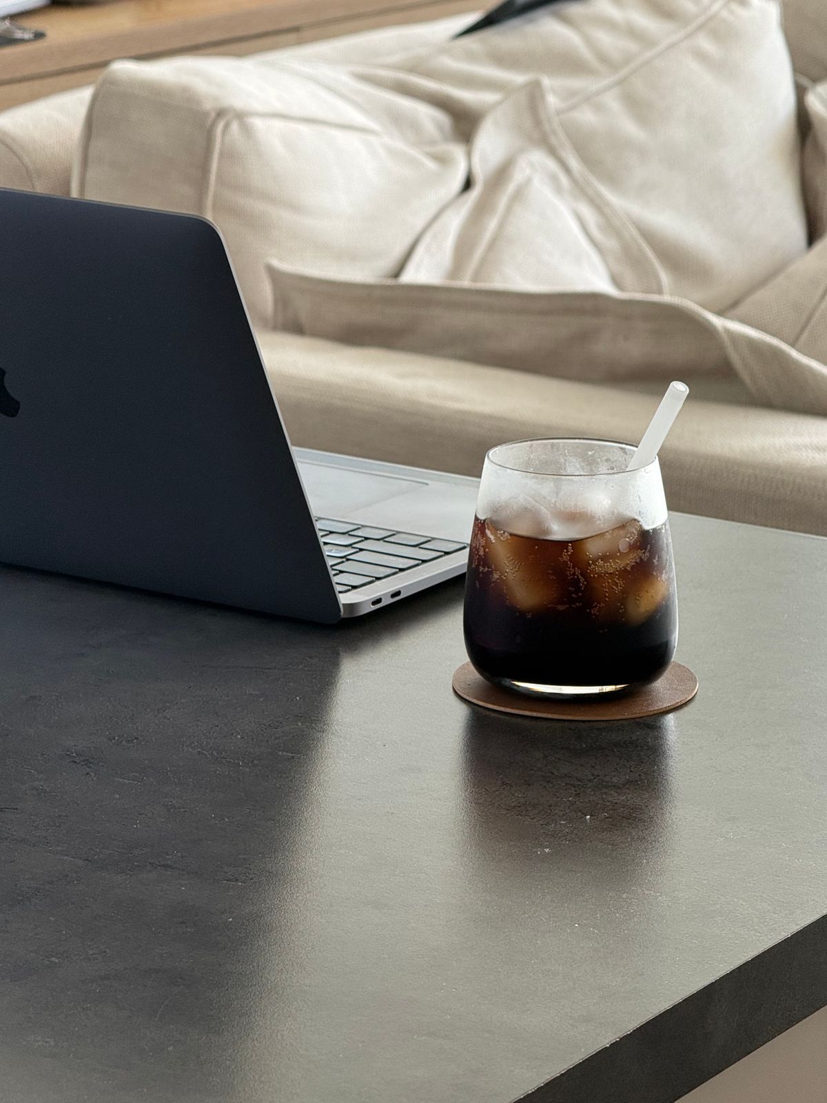 Luxurious desktop setup with dark laptop and drink, symbolizing seamless workflow and automated business efficiency for high-end clients.