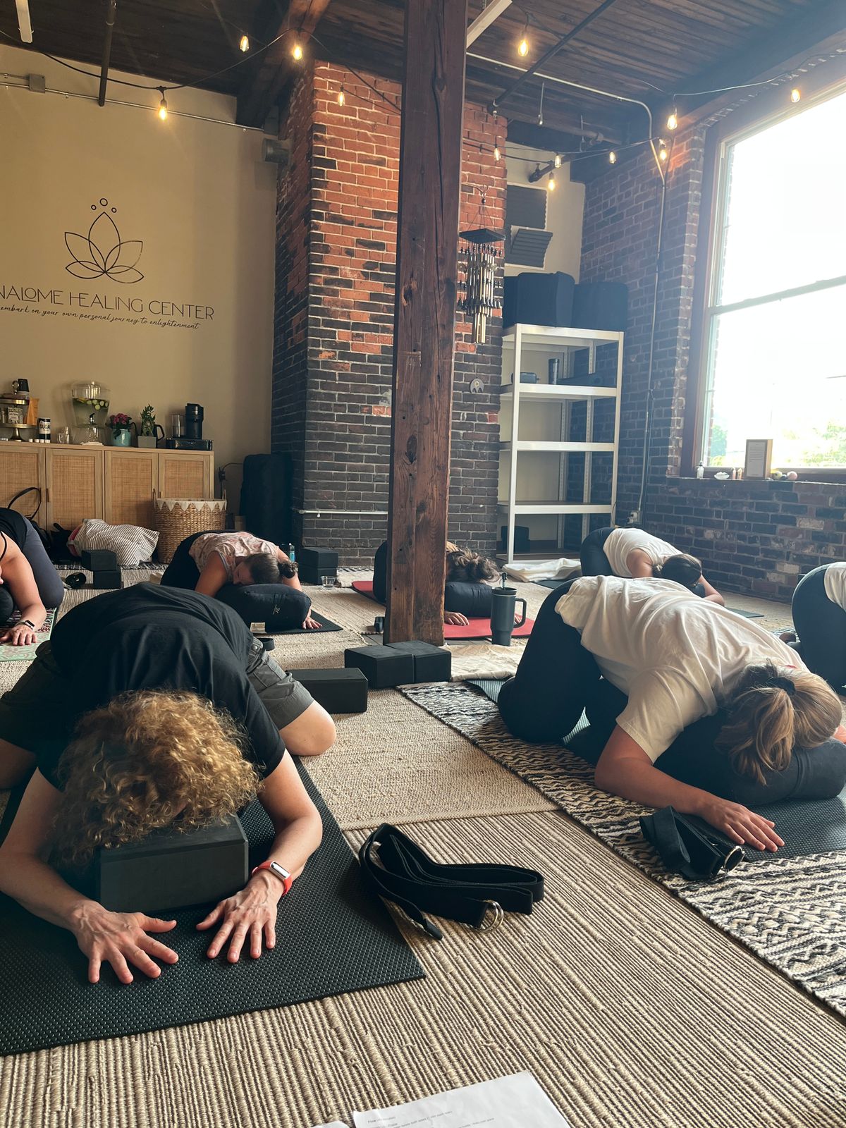 Participants in a Restore & Receive at Blue Jay Healing studio, resting on yoga mats during a guided meditation and Reiki energy practice that combines gentle yoga, deep relaxation, and holistic healing.