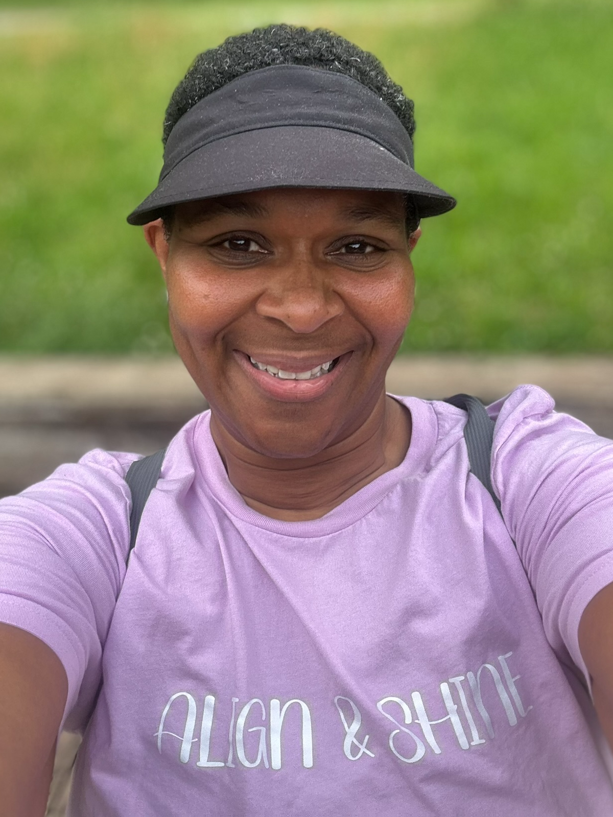 Nina Wright standing and smiling while wearing a lilac Align & Shine t-shirt.