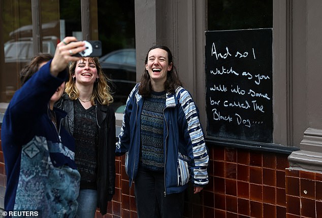 Fans take photos outside the now famous pub. Lyrics from Taylor Swift's songs can be seen on a blackboard in the window