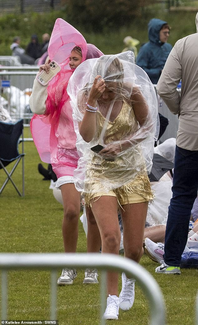 Two fans covered themselves with waterproof coats as they bore out the bad weather ahead of Friday night's gig