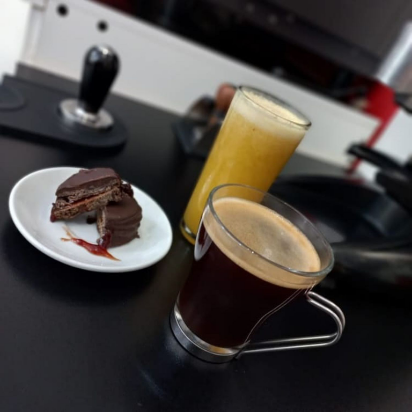 Un americano acompañado de un jugito de naranja y su alfajor de frambuesa.