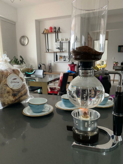 Un delicioso café en sifon con un pan de canela.
