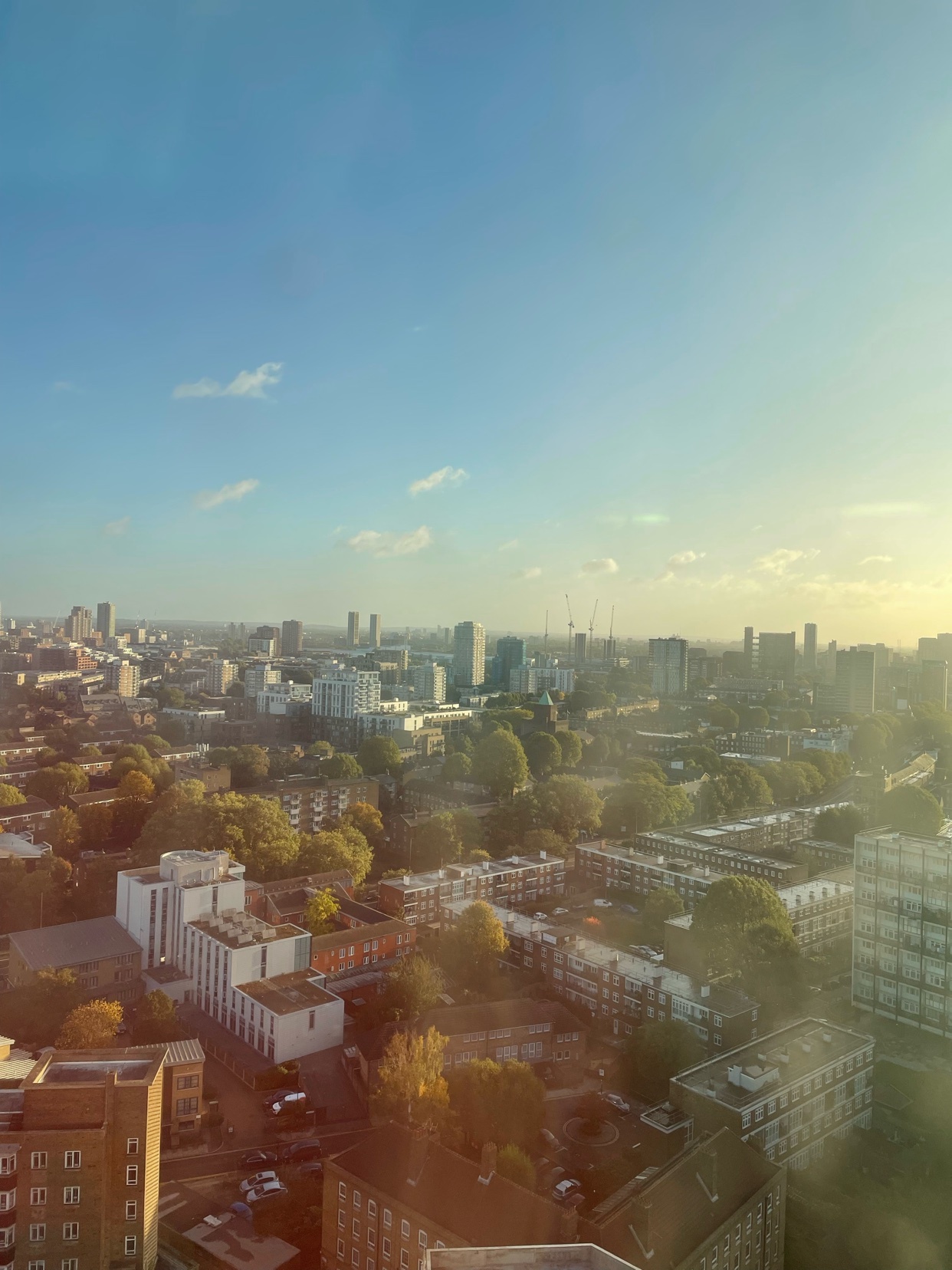 An aerial view of a cityscape under a bright blue sky. The photo captures a sprawling urban landscape with numerous buildings and structures.