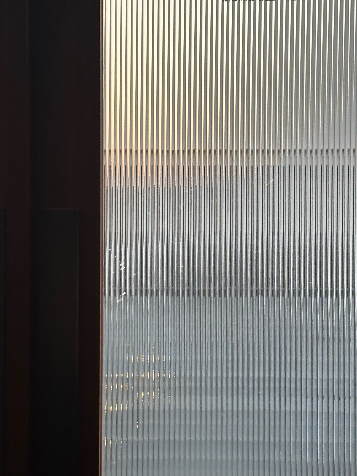 A close-up shot of fluted glass with vertical lines, creating an abstract and minimalist texture.