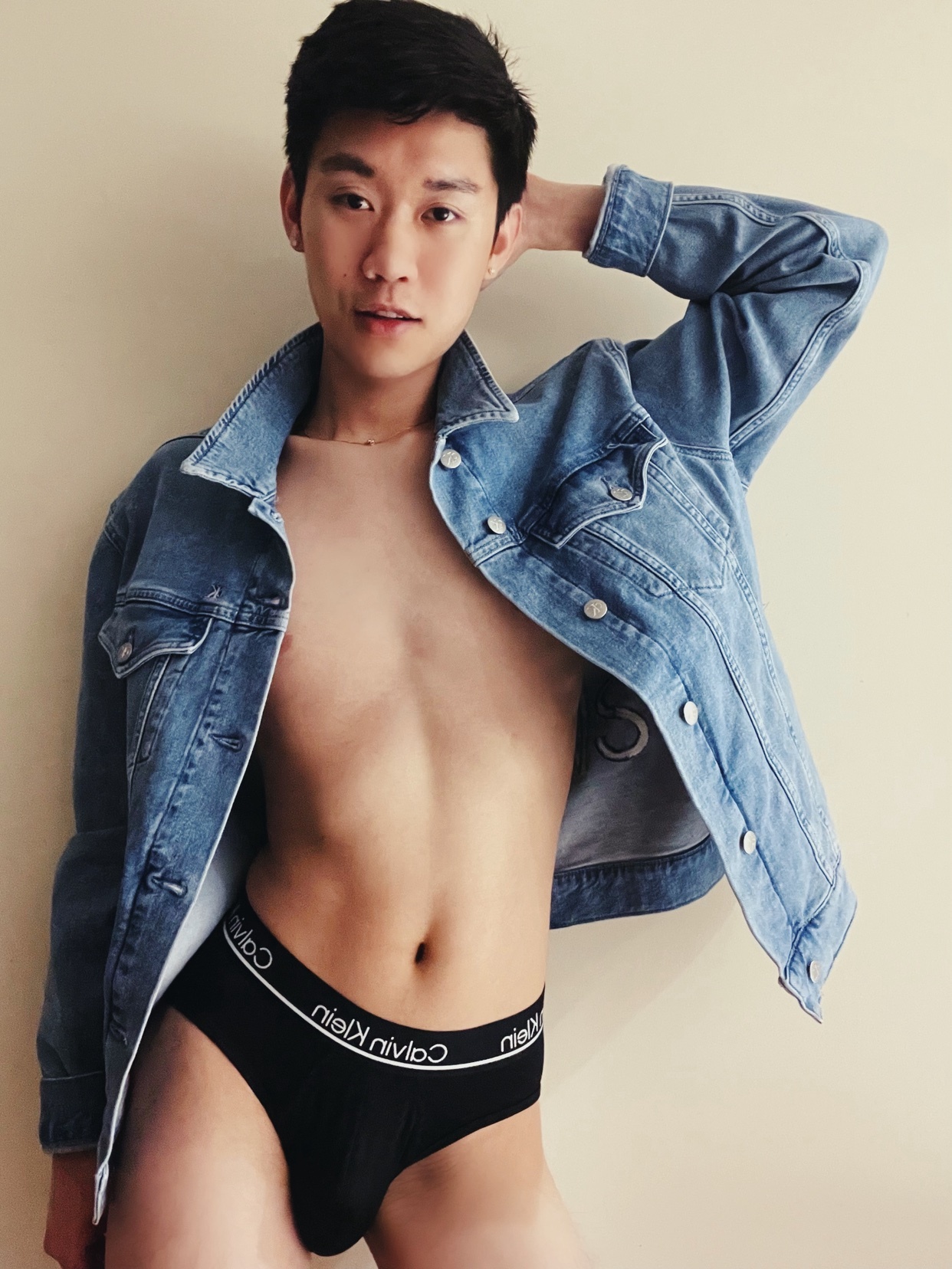 A man poses in a denim jacket and Calvin Klein underwear. The photo showcases a modern and stylish aesthetic.