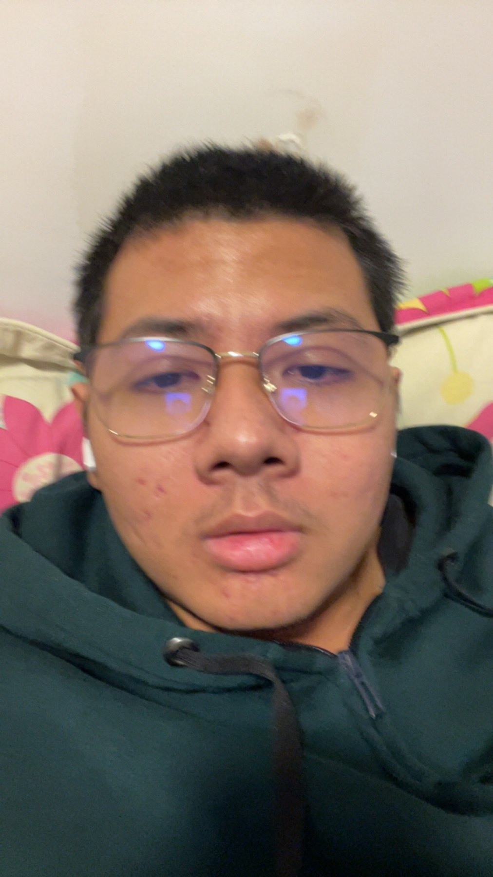 A selfie of a man with glasses and dark hair. He is wearing a green hoodie.