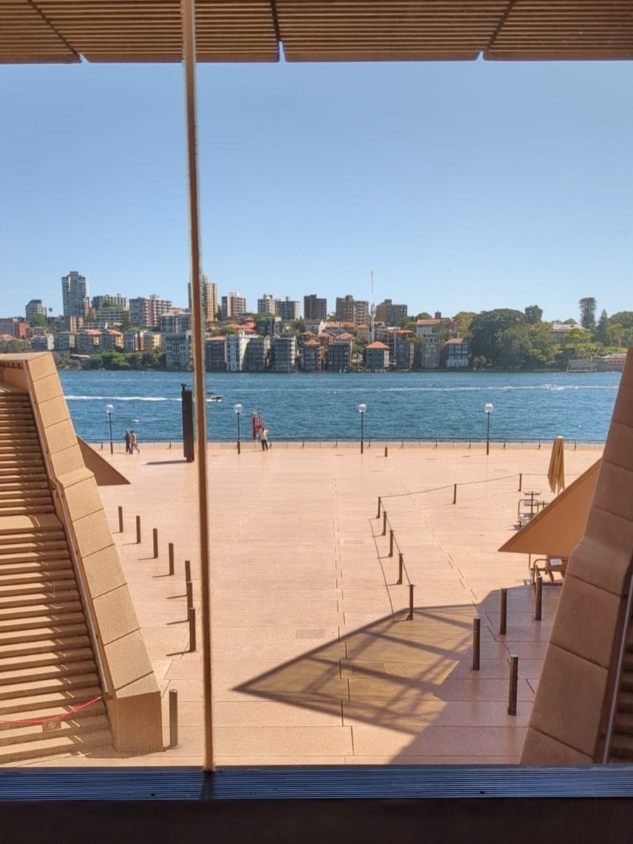 A scenic view of a city skyline and waterfront, framed by the unique architecture of a modern building. The image captures the essence of urban beauty and travel.