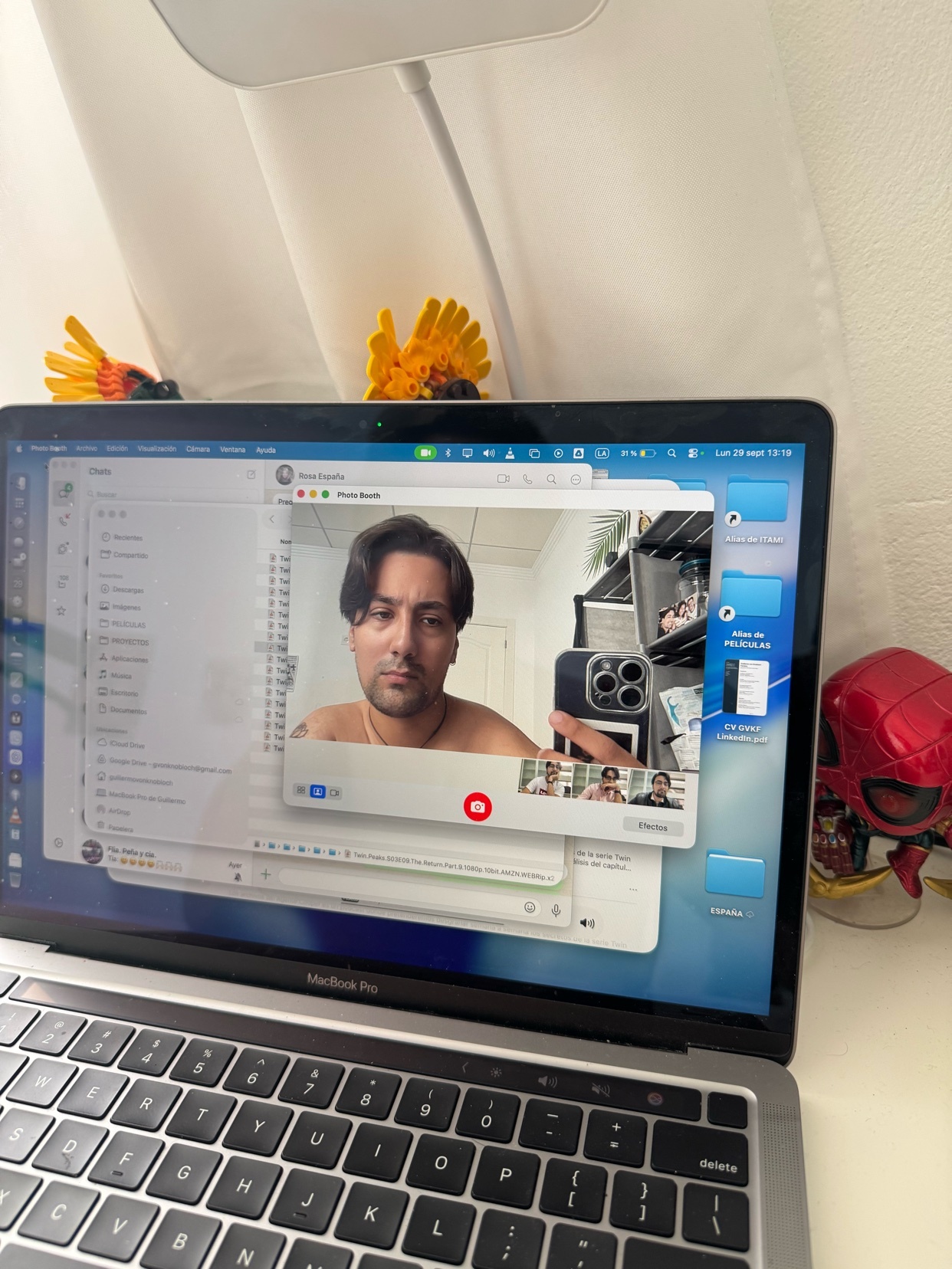 A man is on a video call on his laptop. He is shirtless and looking at the camera.