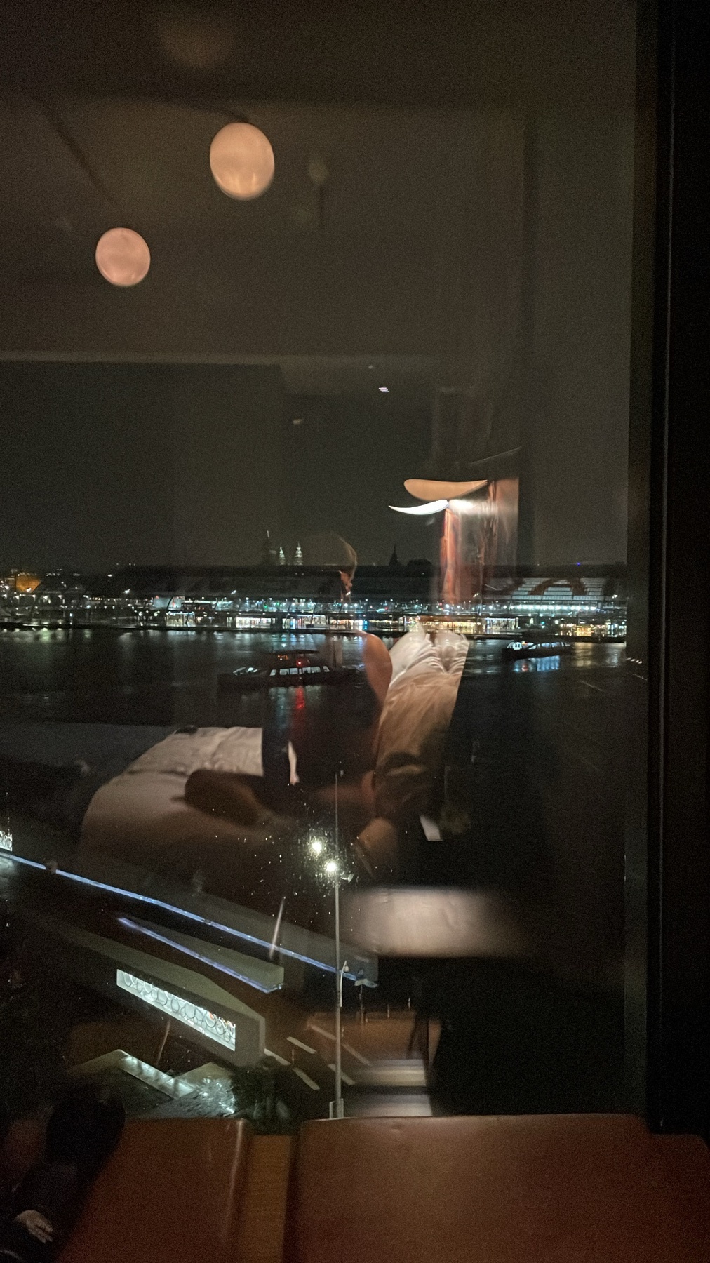 A nighttime cityscape is reflected in a window. The interior of a room is also visible.
