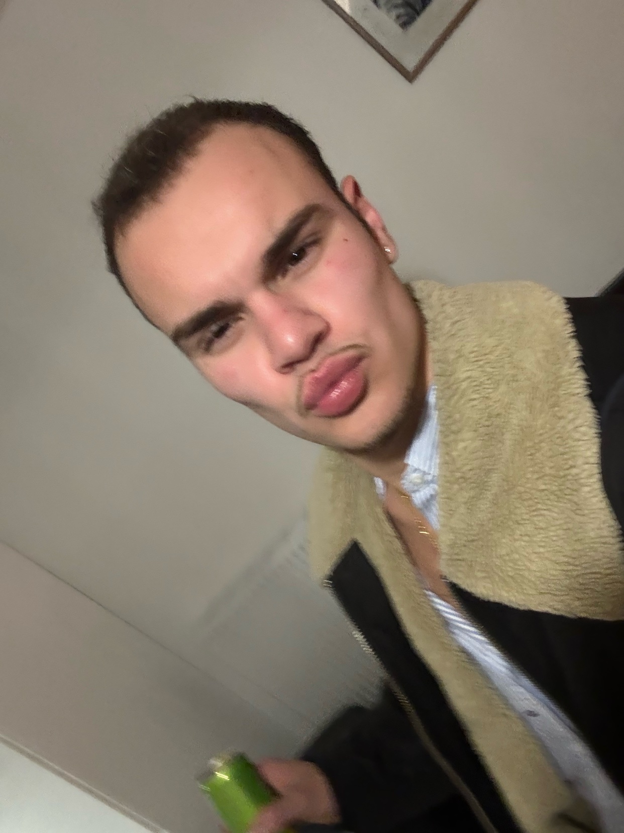 A man takes a selfie at a party. He is wearing a jacket and looking at the camera.