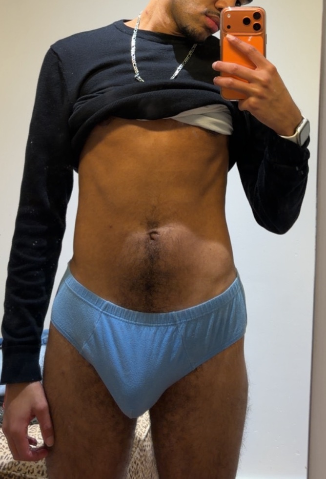 A man takes a mirror selfie, shirtless and wearing blue underwear. The photo highlights his physique.
