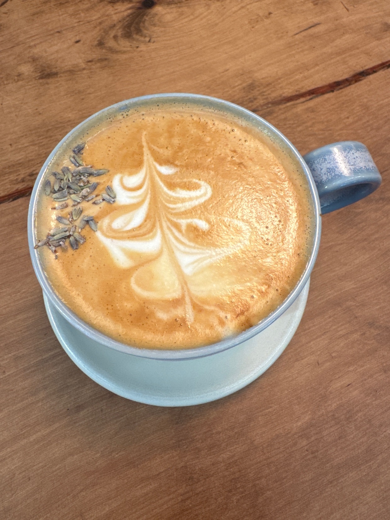 A close-up shot of a beautifully crafted latte with intricate latte art. The coffee is garnished with lavender and served in a stylish ceramic mug.